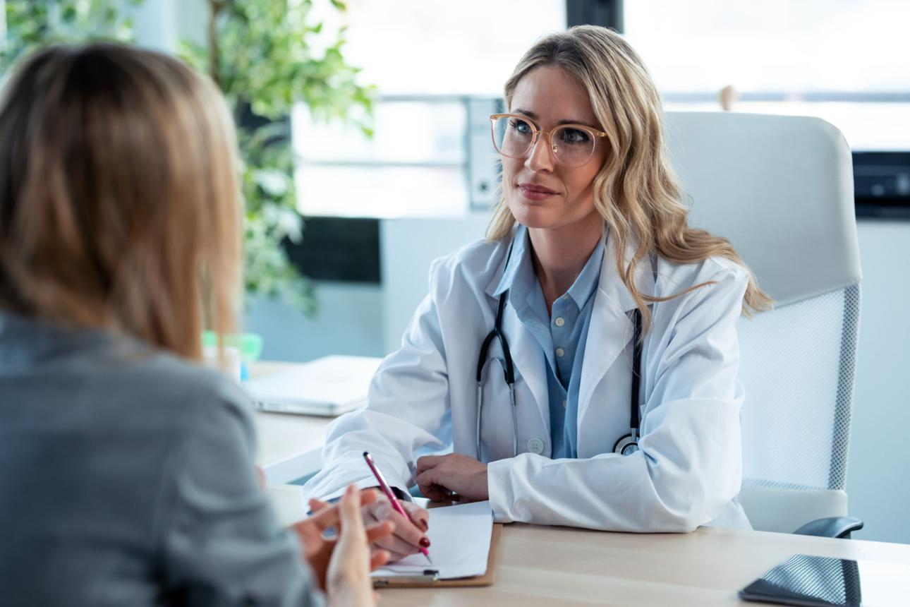 Médecin en blouse blanche écoutant une patiente lors d'une consultation — illustration du bilan d'incontinence