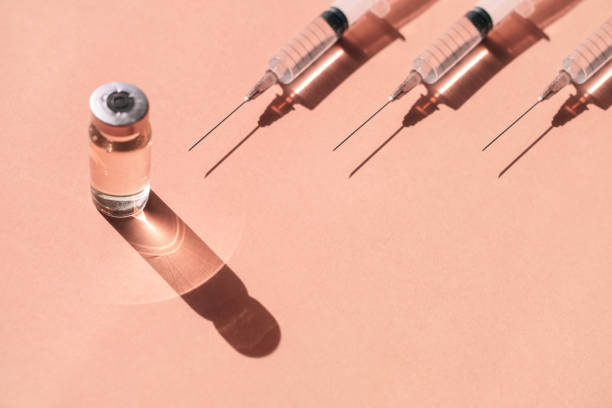 Flacon de toxine botulique et seringues sur un fond rose corail