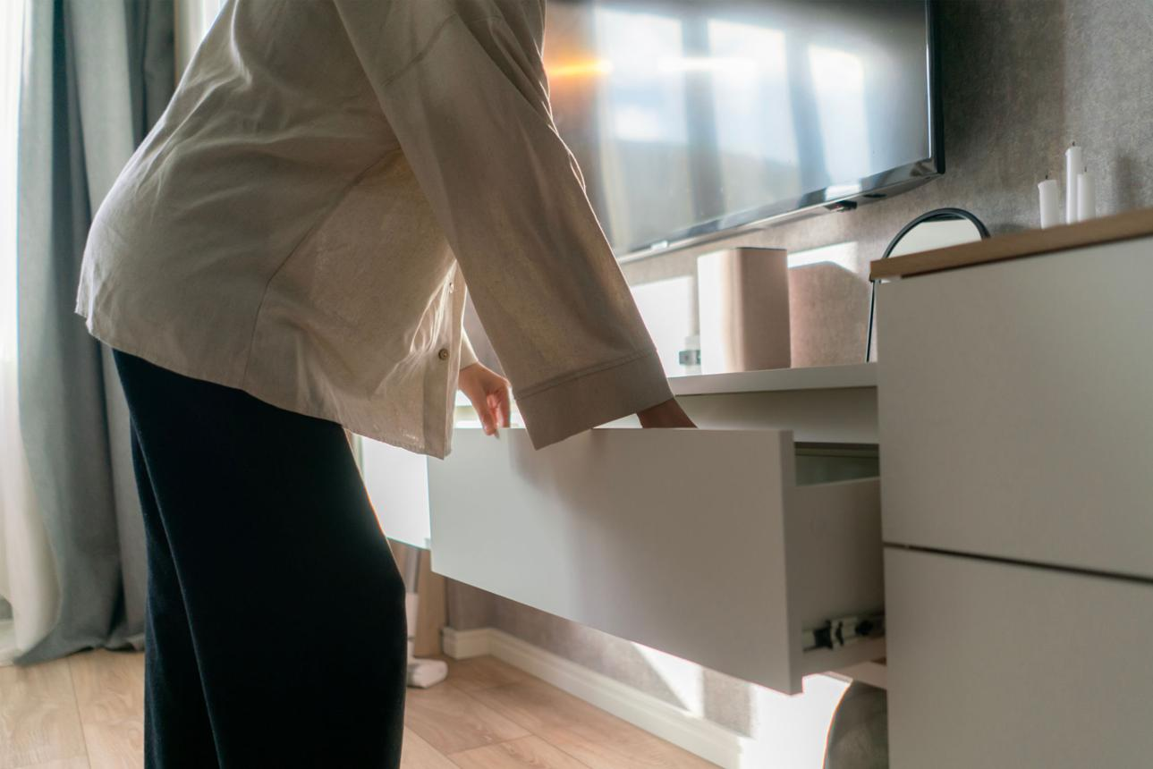 Personne ouvrant un tiroir contenant ses protections d'incontinence dans une chambre lumineuse